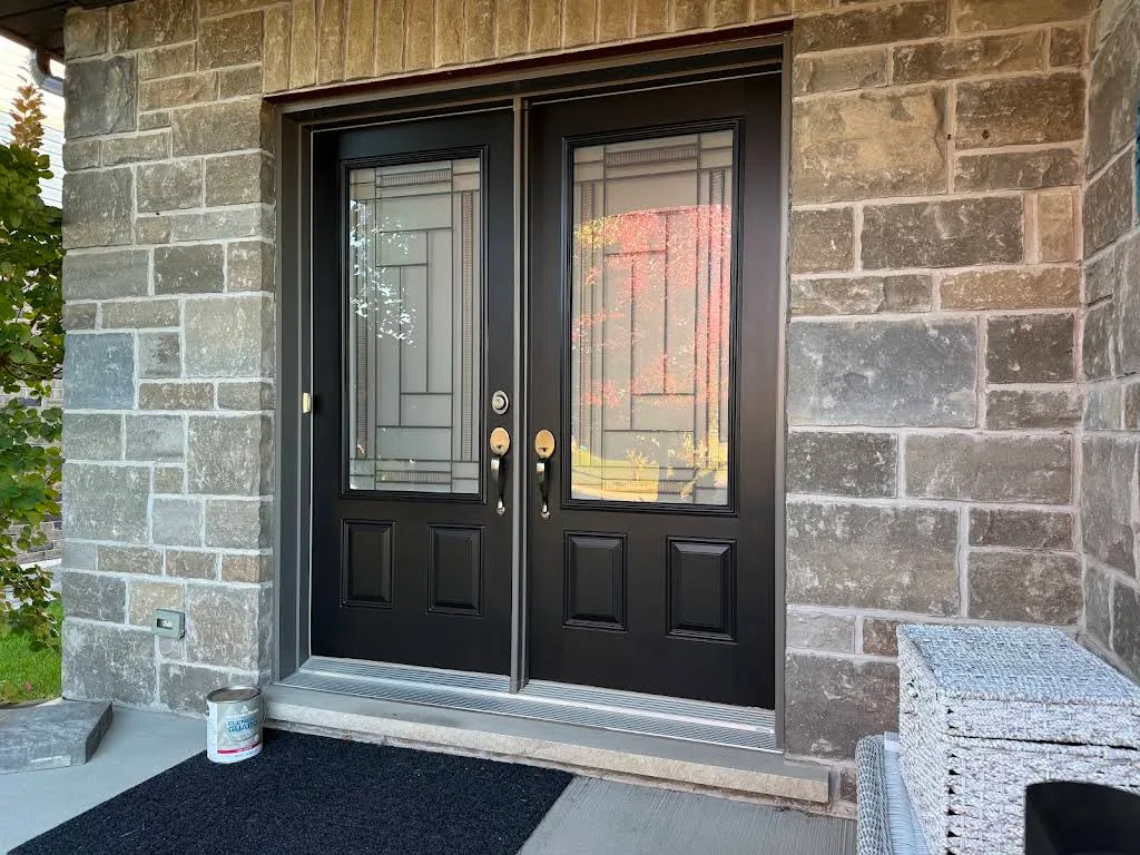 Painted black double entry doors with decorative glass and stone surround